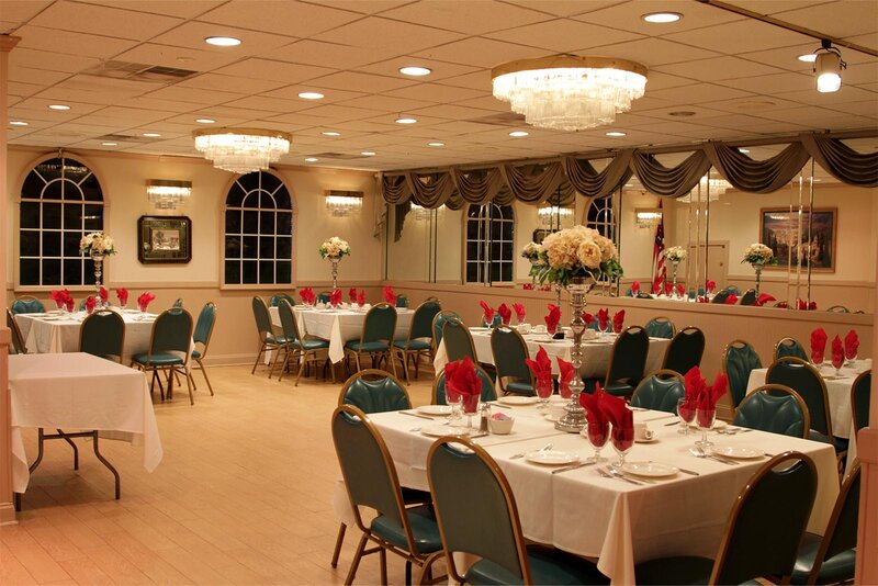 Party room with set tables decorated with red linen and flower vases